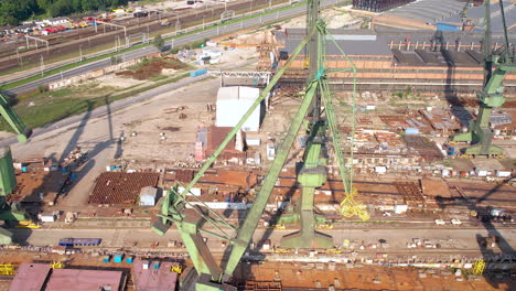 Aerial-dolly-view-across-big-green-cranes-in-Gdansk-shipyard,-Poland
