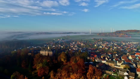 Aerial-view-of-historic-city-in-Germany-with-Castle-and-autumnal-trees-during-foggy-day