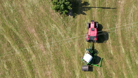 Aerial-view-looking-down-over-tractor-wrapping-bale-in-plastic-on-agricultural-farmland