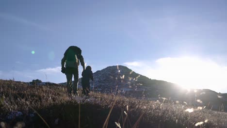 Cinematic-shot-of-child-and-grandfather-hiking-in-mountain-during-crisp-and-sunny-autumn-morning