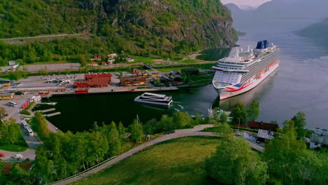 Beautiful-drone-shot-over-the-town-of-Aurlandsfjord-in-Flam,-Norway-on-a-beautiful-spring-day-with-the-view-of-a-white-cruise-ship-docked