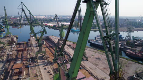 Aerial-view-orbiting-large-green-port-cranes-in-Gdansk-shipyard,-Poland