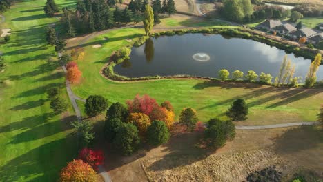 Drohnenansicht-Eines-Golfplatzwasserspiels-Mit-Springbrunnen-Während-Eines-Hellen-Herbstsonnenaufgangs