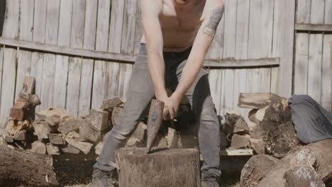 Close-up-slow-motion-footage-of-a-shirtless-man-splitting-a-log