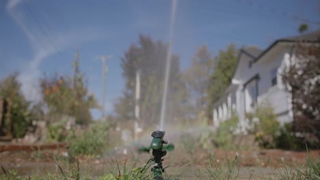 Wide-footage-from-the-back-of-a-sprinkler-watering-a-yard-with-a-small-rainbow