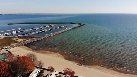 A-wide-aerial-flyover-of-Harbor-Park-Marina-on-Lake-Huron-in-Tawas-City,-Michigan-on-a-sunny-autumn-day