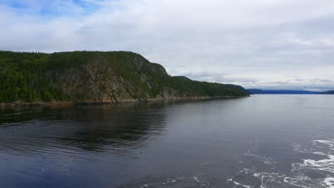 View-of-mountains-from-the-stern-of-a-ship-cruising-along-Saguenay-Fjord-outside-of-La-Baie,-QC,-Canada