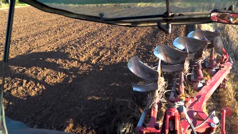 Tractor-pulling-reversible-plough-on-the-field,-cultivating-soil-for-season