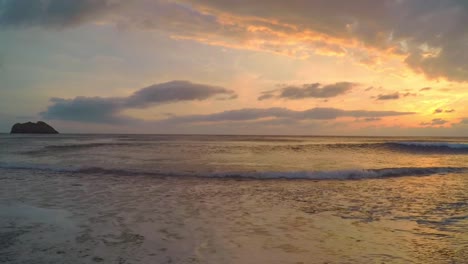 Ein-Wunderschöner-Sonnenuntergang-An-Einem-Griechischen-Strand-Mit-Ruhigen,-Plätschernden-Wellen-Und-Einer-Felsformation-Im-Ozean