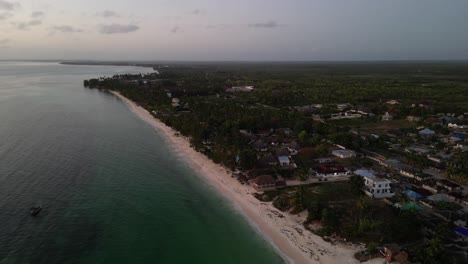 Uroa-beach-resorts-and-homes-in-Zanzibar-Island-Tanzania-Africa-during-sunset,-Aerial-pan-left-shot
