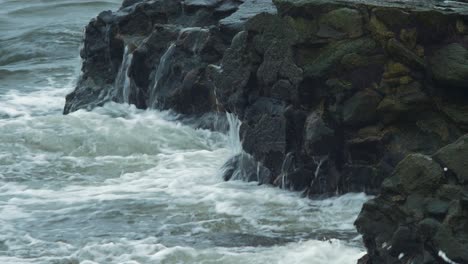 Huge-rolling-waves-crashing-along-pier-wall-and-stones,-overcast-autumn-day,-climate-changes,-closeup-shot