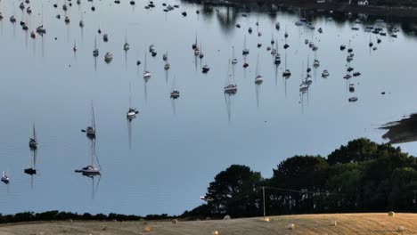 Boats-Moored-On-Water-Bales-In-Field-Cornwall-Evening-Aerial-Summer-Landscape