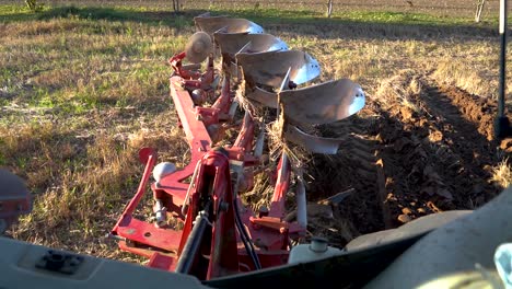 Farmer-lowering-reversible-plow-in-the-ground,-plowing-soil-for-seeding