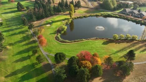 Breite-Luftaufnahme-Eines-Golfplatz-Wasserspiels-Während-Eines-Herbstsonnenaufgangs