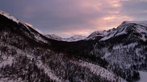 Sunset-drone-view-of-colorful-clouds-and-a-snow-covered-mountain-valley