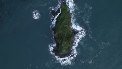 High-angle-view-of-a-tiny-green-island-in-the-south-pacific-ocean-with-sea-birds-flying-underneath