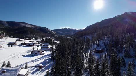 Drohnenansicht-Von-Schneebedeckten-Häusern-In-Einem-Tal-Mit-Bergen