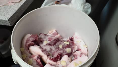 Pork-salting-process-in-a-bucket-with-garlic