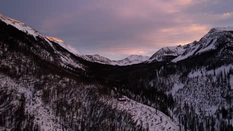 Sunset-drone-view-of-a-snow-covered-mountain-valley-during-golden-hour