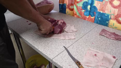 Person-Chopping-Raw-Pork-Meat-On-The-Kitchen-Table-Using-Sharp-Knife