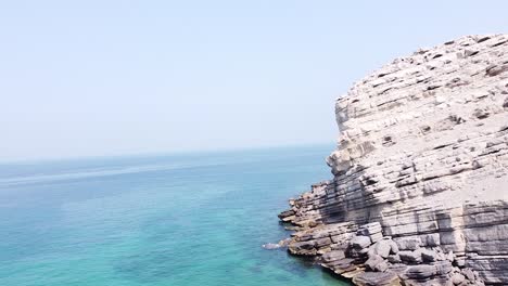 Drone-shot-of-rocky-mountain-cliff-by-the-sea-in-Oman