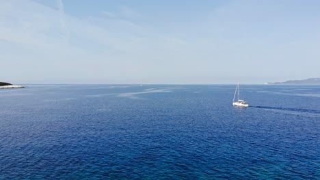 Vista-Aérea-Del-Barco-Navegando-En-El-Mar-Azul-Hacia-La-Playa-Emplisi-En-Grecia