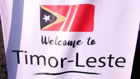 Primer-Plano-Del-Cartel-De-Bienvenida-A-Timor-Leste-Con-Bandera-Timorense-Para-Turistas-Que-Visitan-La-Capital-Dili,-Timor-Leste-En-El-Sudeste-Asiático