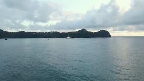 Large-yacht-in-front-of-a-long-peninsula-covered-by-thick-rainforest