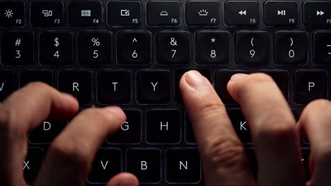 Close-up-and-top-view-footage-of-young-businessman-hands-busy-working,-searching-and-studying-by-typing-on-glowing-keyboard-in-the-dark-for-send-emails-and-surf-on-a-web-browser