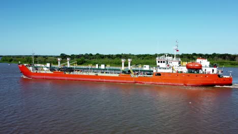 Side-Shot-Of-Huge-Long-Red-Commercial-Ship-Crossing-Narrow-Arm-Of-River,-Paraguay