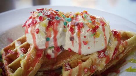 Confetti-Belgian-waffles-filled-with-fruity-pebbles-rice-cereal-and-topped-with-ice-cream-and-syrup,-close-up-4K
