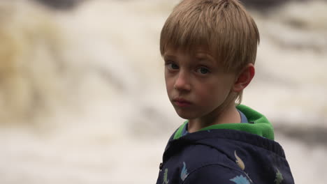 Slow-motion-portrait-of-a-little-boy-watching-the-fury-of-white-water-rapids