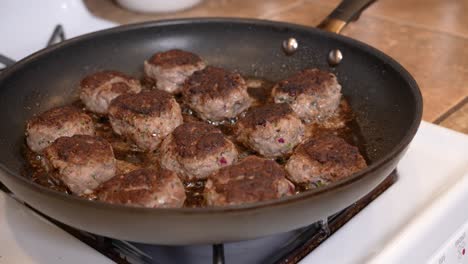 Spiced-lamb-patties-frying-in-a-pan-on-the-stove-in-hot-olive-oil---side-view-LAMB-PATTY-SERIES
