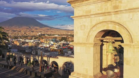 Arequipa-bell-tower-and-volcano-during-sunset-drone