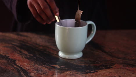 Placing-tea-cup-on-table-and-removing-the-teabag-from-a-colorful-cup-of-tea