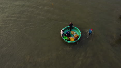 Grupo-De-Pescadores-Vietnamitas-Que-Se-Preparan-Para-Un-Viaje-De-Pesca-En-Un-Barco-Tradicional-Redondo,-Toma-Aérea-De-Drones