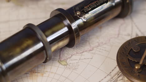 An-antique-brass-telescope-with-sundial-and-compass-on-a-vintage-map-of-the-world-for-plotting-adventure