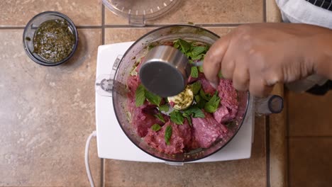 Adding-mint-leaves-to-a-food-processor-with-ground-lamb-meat-to-mince-together---overhead-view-LAMB-PATTY-SERIES