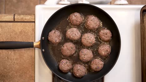 Spiced-lamb-patties-frying-in-a-pan-on-the-stove-in-hot-olive-oil---overhead-view-LAMB-PATTY-SERIES