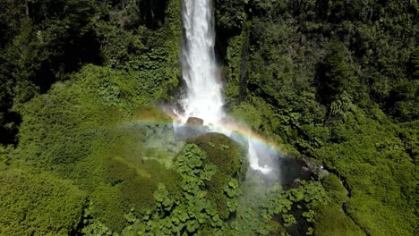 General-aerial-orbit-of-the-waterfall-at-El-Salto-El-Leon-with-a-continuous-rainbow-and-surrounded-by-vegetation---drone-shot
