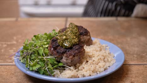 A-serving-of-spiced-lamb-patties-on-a-bed-of-fresh-herbs-and-quinoa-on-a-plate-with-topped-with-a-mint-sauce---LAMB-PATTY-SERIES
