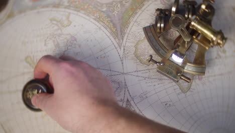 Ein-Mann-Verwendet-Einen-Antiken-Kompass,-Um-Einen-Kurs-Auf-Einer-Alten-Weltkarte-Mit-Einem-Sextanten-Im-Hintergrund-Zu-Zeichnen