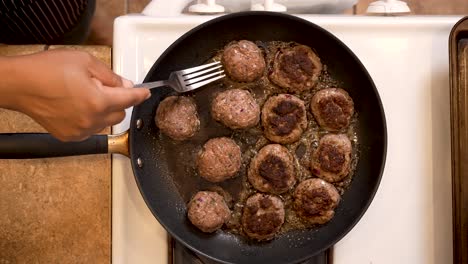 Frying-spiced-lamb-balls-in-a-pan-on-the-stove-and-smashing-them-into-patties-with-a-fork---overhead-view-LAMB-PATTY-SERIES