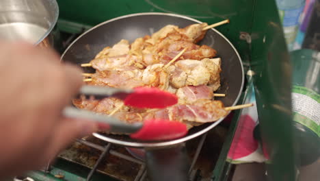Cooking-mouthwatering-chicken-souvlaki-skewers-on-a-hot-pan-over-a-camp-stove