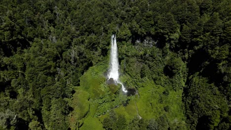 Panoramic-orbit-of-the-waterfall-El-Salto-El-Leon-in-the-south-of-chile-with-vegetation-around-it-on-a-sunny-day---aerial