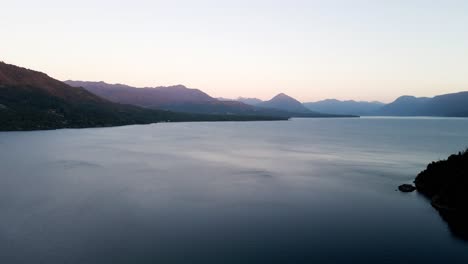 Relaxing-panoramic-view-at-the-blue-hour-of-lake-calafquen-in-southern-chile-with-movement-in-its-waters-and-the-mountains-on-the-horizon---drone-shot