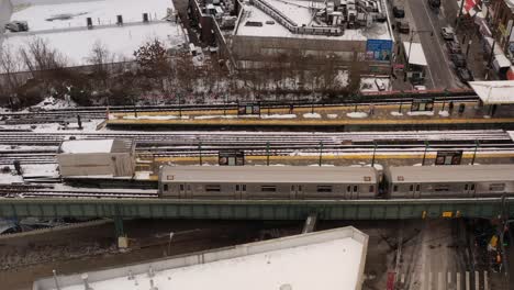 A-aerial,-profile-view-a-subway-train-stopped-at-a-station-on-a-snowy-day