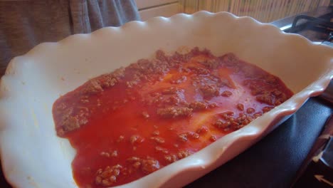 Lasagne-Pasta-Sheets-Being-Placed-On-top-Of-Hot-Steamy-Bolognese-Sauce-In-Dish