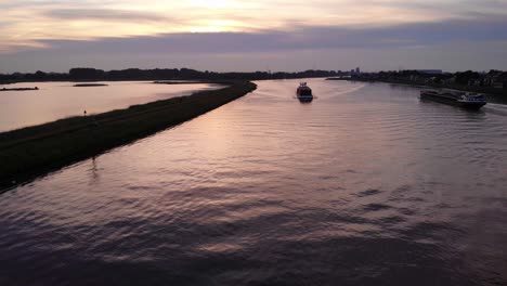 Aerial-Sunset-View-Above-River-Noord-Of-Cargo-Ship-Travelling-Past-Crezeepolder-Nature-Reserve-At-Ridderkerk-In-Netherlands