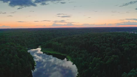 Aerial-View-Of-Woodland-With-Winding-River-Reflecting-Cloudy-Sky-After-Sunset